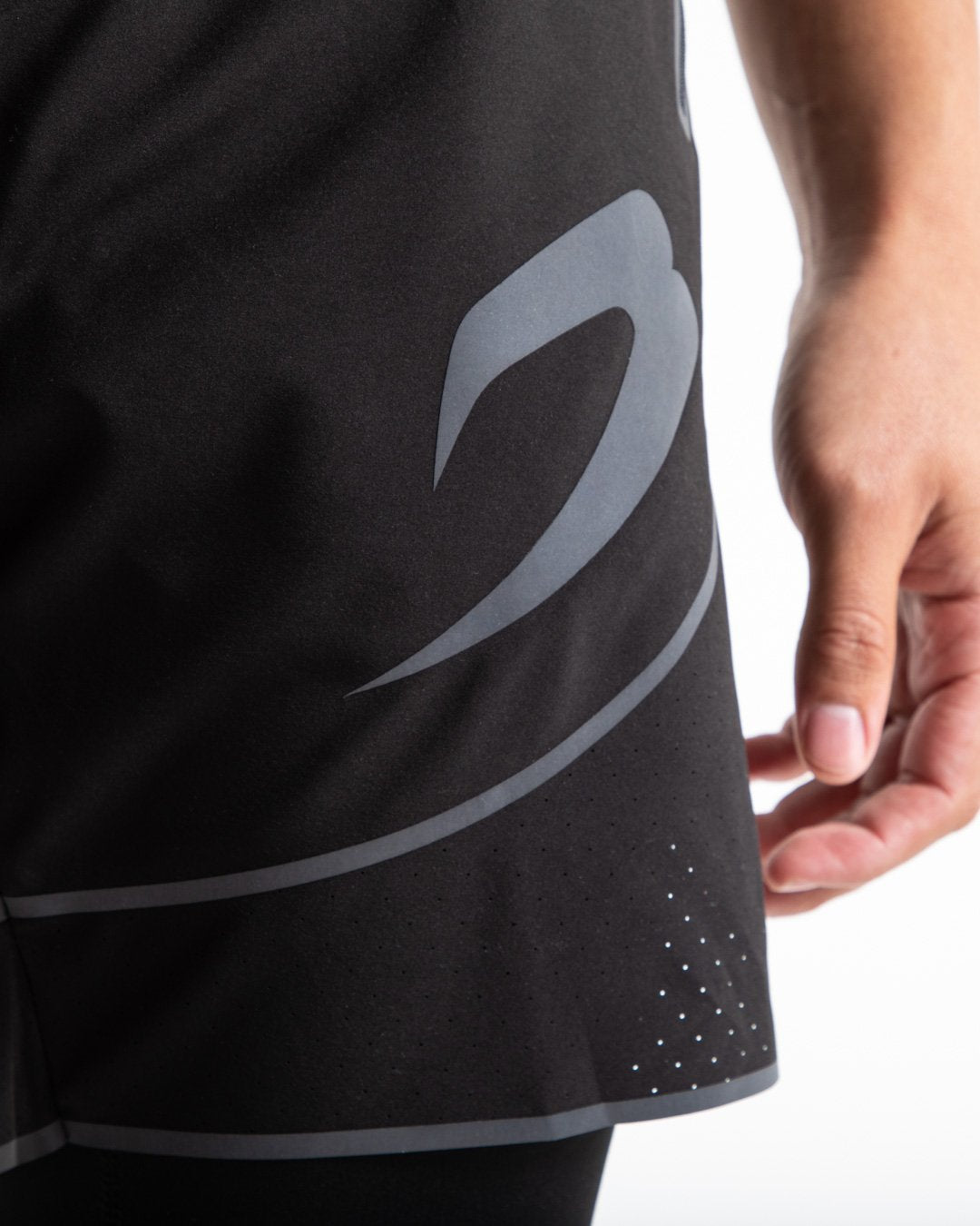 Man in black shorts with compression shorts underlayer with reflective detailing and side zipped pockets