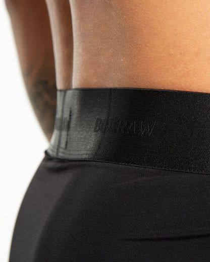 Man in black nylon slim fit boxers with white strike logo on waistband
