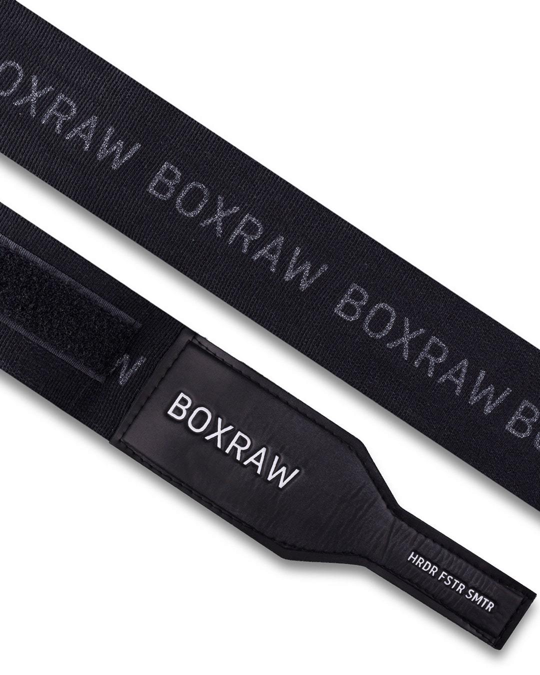 Black fabric boxing handwraps that is 4.5 metres in length with a leather velcro strap embossed with a white boxraw strike logo.