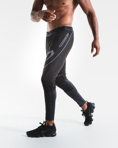 Man in slim fitting black lightweight tracksuit bottoms with reflective detailing and side zipped pockets