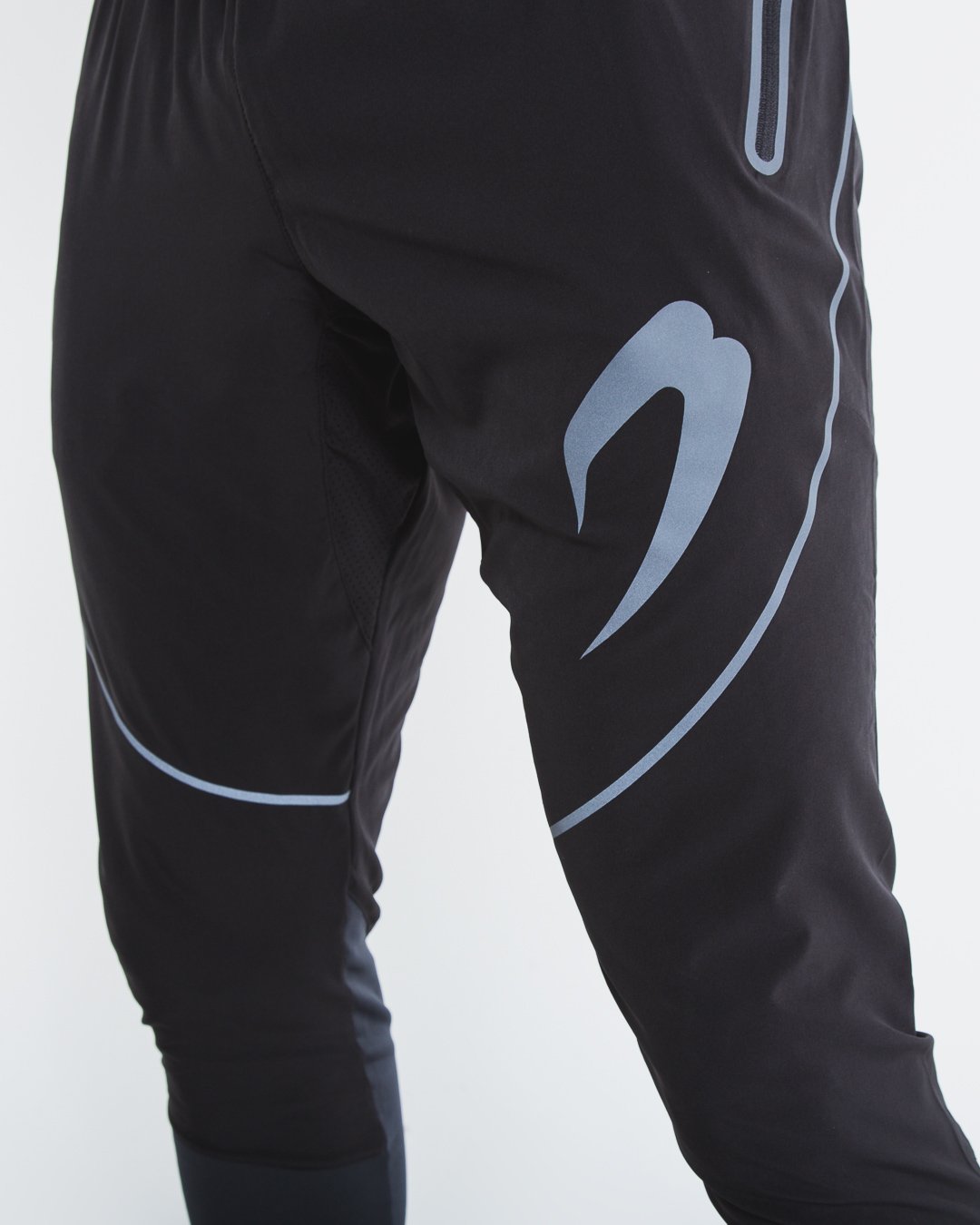 Man in slim fitting black lightweight tracksuit bottoms with reflective detailing and side zipped pockets