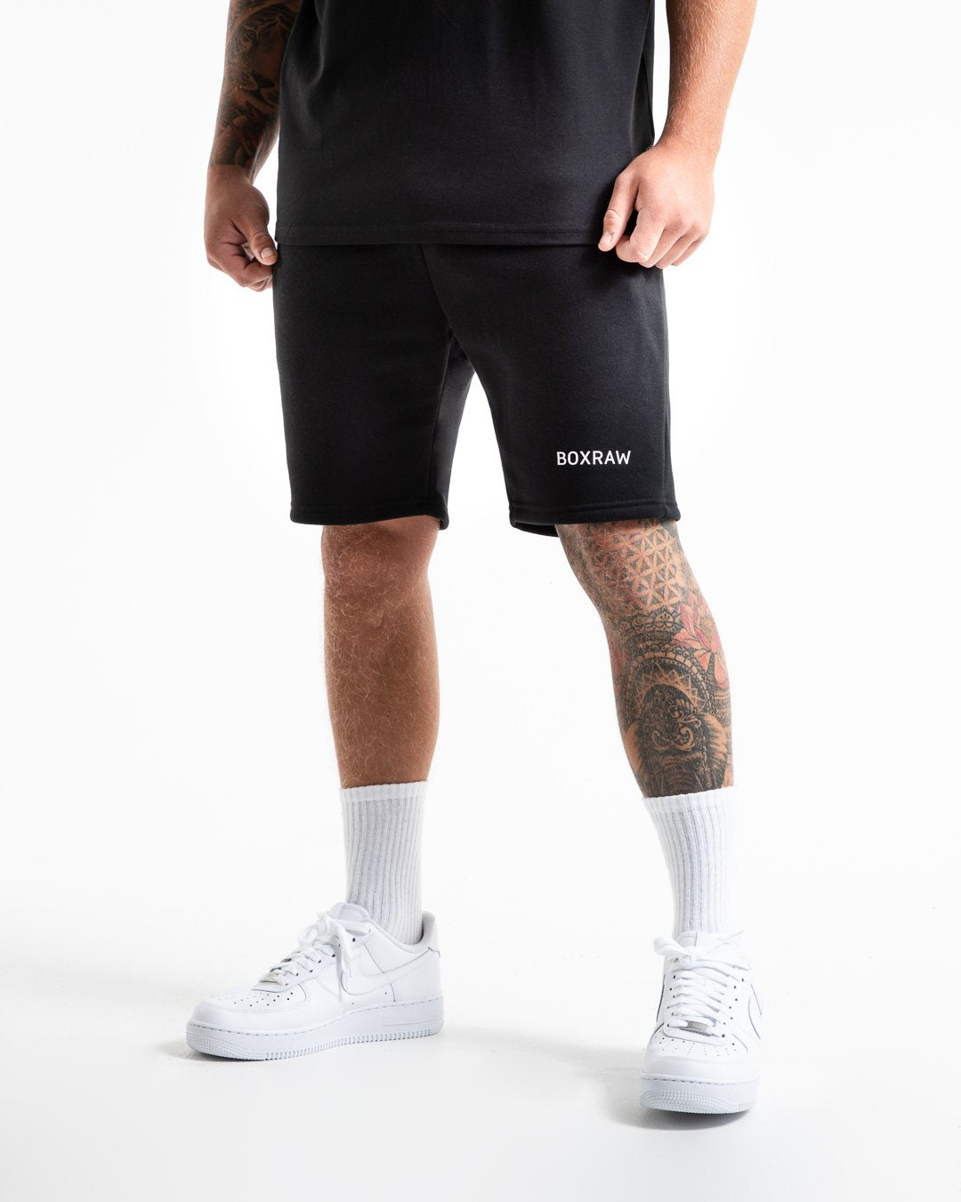 Man in black tracksuit style shorts with a white 3D boxraw logo as well as side zipped pockets made from a cotton/poly blend.