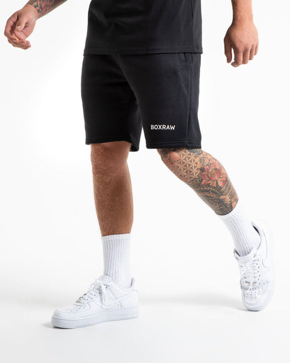 Man in black tracksuit style shorts with a white 3D boxraw logo as well as side zipped pockets made from a cotton/poly blend.