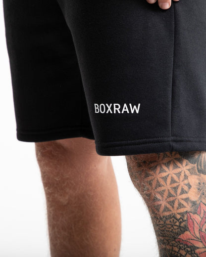 Man in black tracksuit style shorts with a white 3D boxraw logo as well as side zipped pockets made from a cotton/poly blend.