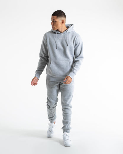 Man in relaxed fit grey tracksuit bottoms with a white 3D boxraw logo as well as side zipped pockets made from a cotton/poly blend.