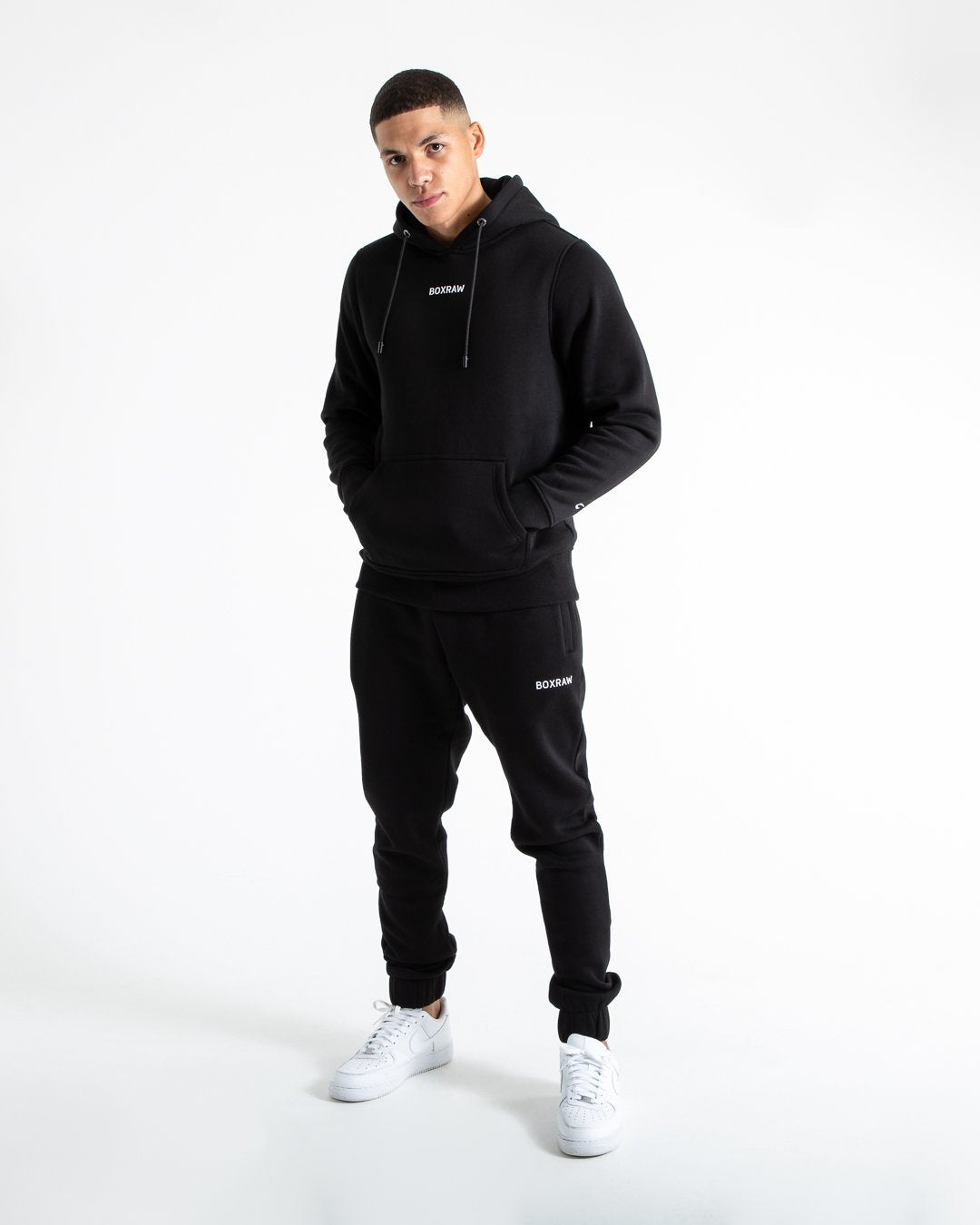 Man in relaxed fit black tracksuit bottoms with a white 3D boxraw logo as well as side zipped pockets made from a cotton/poly blend.