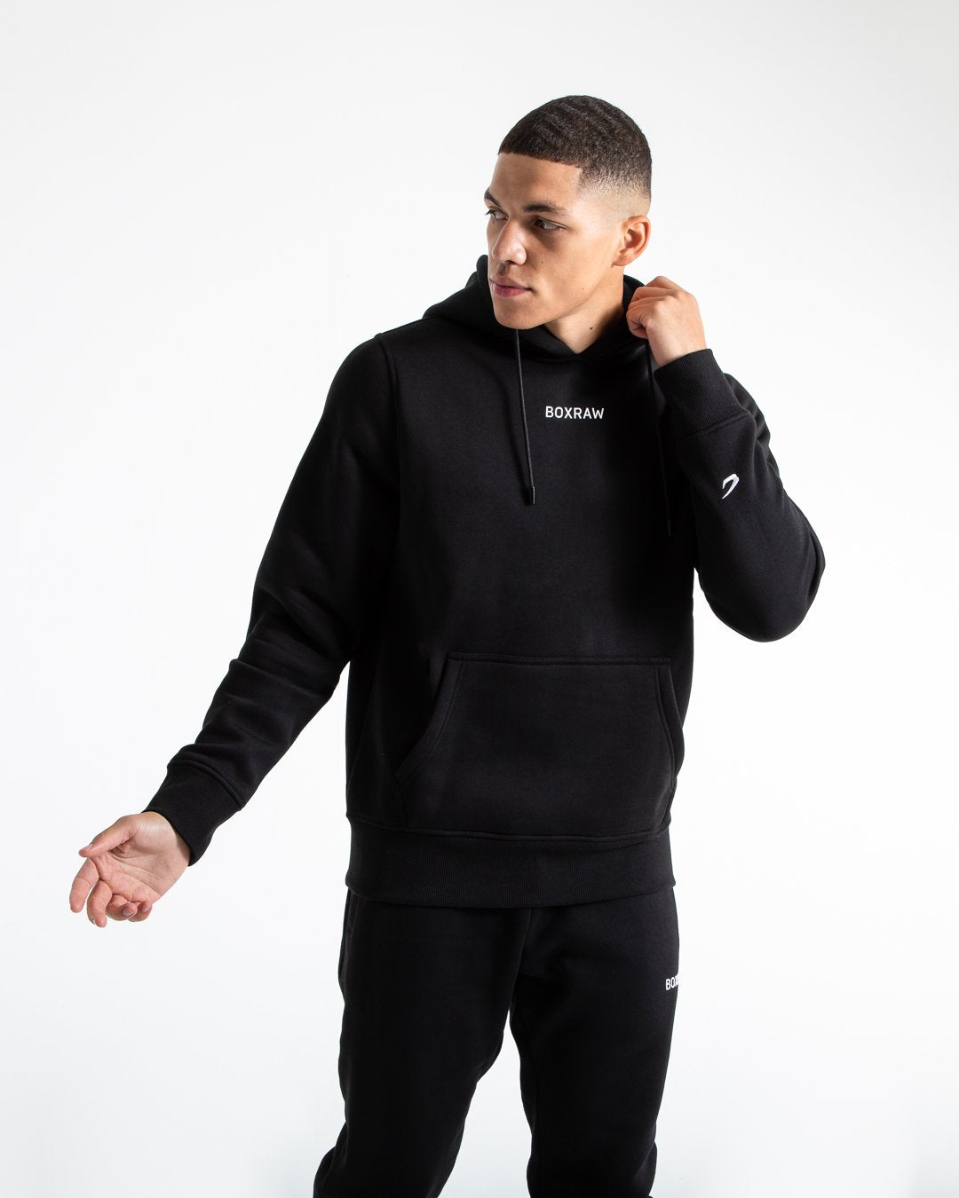 Man in black jumper with hood and kangaroo pouch as well as white 3D boxraw logo on the chest and embroidered strike logos on sleeves.