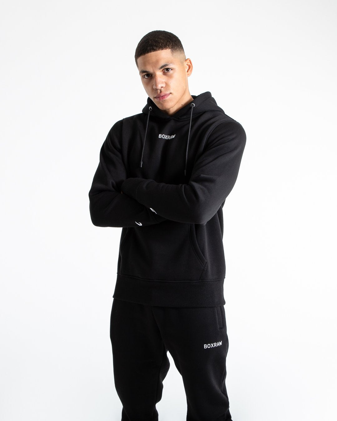 Man in black jumper with hood and kangaroo pouch as well as white 3D boxraw logo on the chest and embroidered strike logos on sleeves.