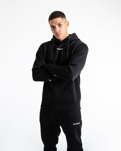 Man in black jumper with hood and kangaroo pouch as well as white 3D boxraw logo on the chest and embroidered strike logos on sleeves.