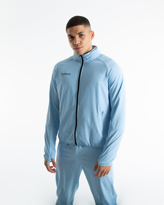 Man in baby blue zipped lightweight tracksuit jacket with a hidden zipped hoodie with black boxraw logo made from polyester.