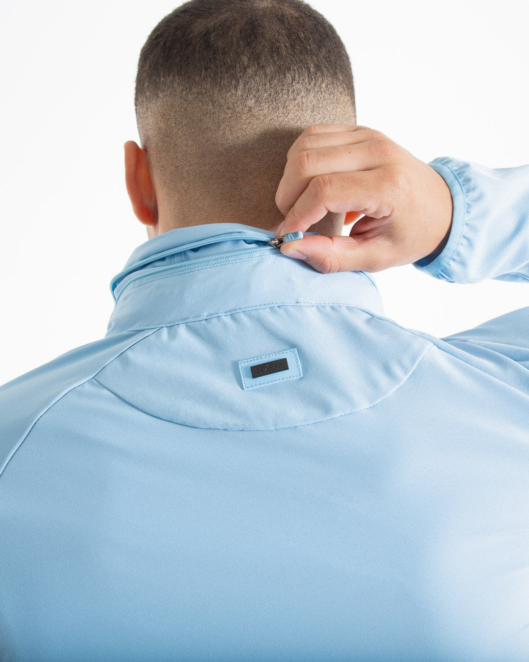 Man in baby blue zipped lightweight tracksuit jacket with a hidden zipped hoodie with black boxraw logo made from polyester.