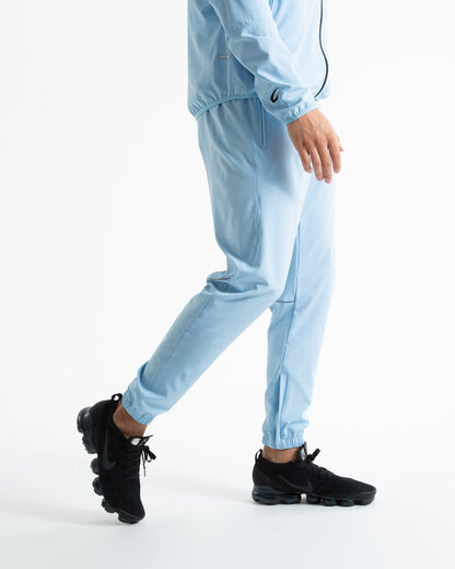 Man in baby blue lightweight tracksuit bottoms with mesh/perforated ventilation panels on the legs with black boxraw logo