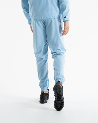 Man in baby blue lightweight tracksuit bottoms with mesh/perforated ventilation panels on the legs with black boxraw logo