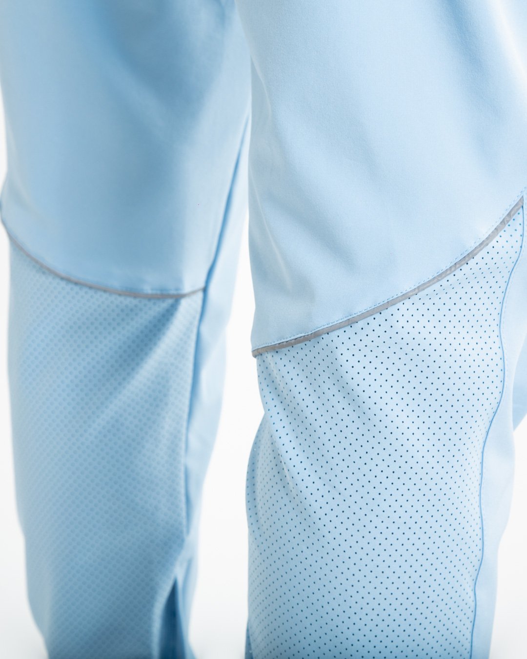 Man in baby blue lightweight tracksuit bottoms with mesh/perforated ventilation panels on the legs with black boxraw logo
