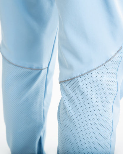 Man in baby blue lightweight tracksuit bottoms with mesh/perforated ventilation panels on the legs with black boxraw logo