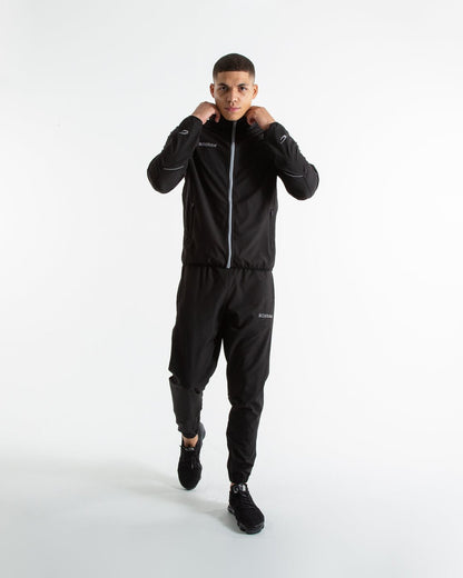 Man in black lightweight tracksuit bottoms with mesh/perforated ventilation panels on the legs with white boxraw logo.