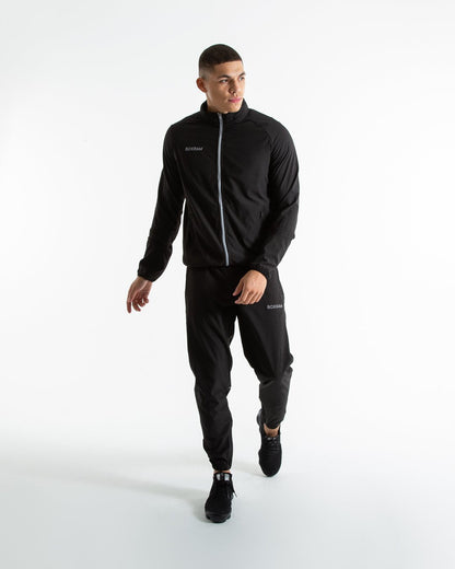 Man in black lightweight tracksuit bottoms with mesh/perforated ventilation panels on the legs with white boxraw logo.