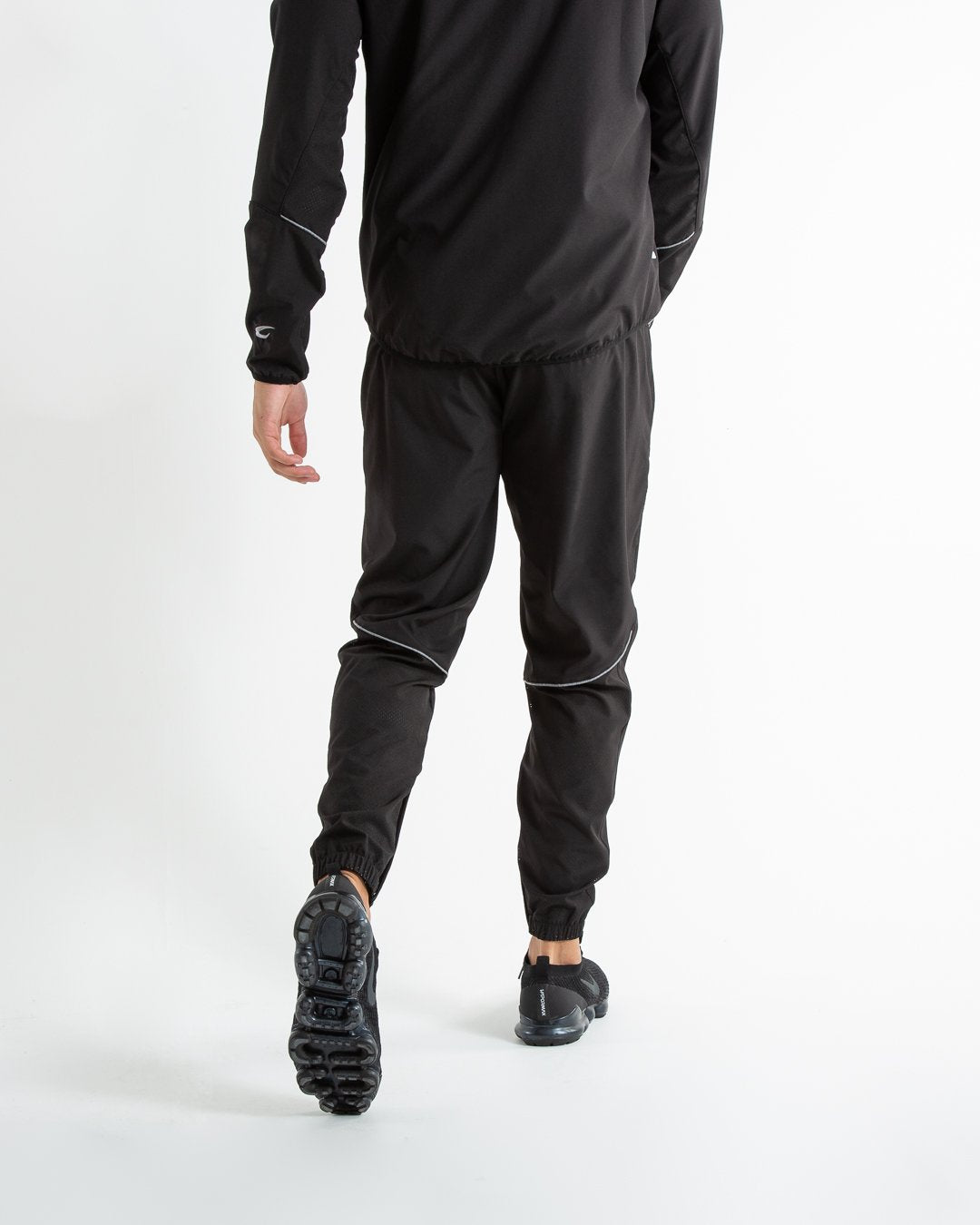 Man in black lightweight tracksuit bottoms with mesh/perforated ventilation panels on the legs with white boxraw logo.