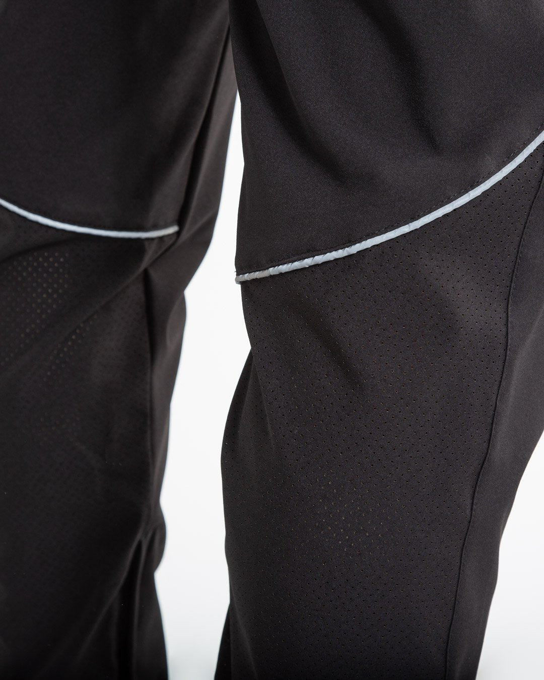 Man in black lightweight tracksuit bottoms with mesh/perforated ventilation panels on the legs with white boxraw logo.