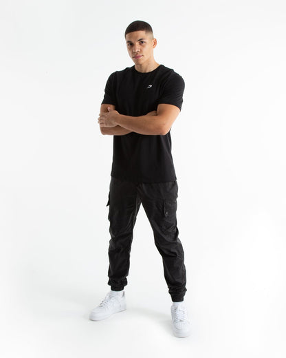 Man in tailored fit black t-shirt with embroidered boxraw strike logo made from stretch cotton.