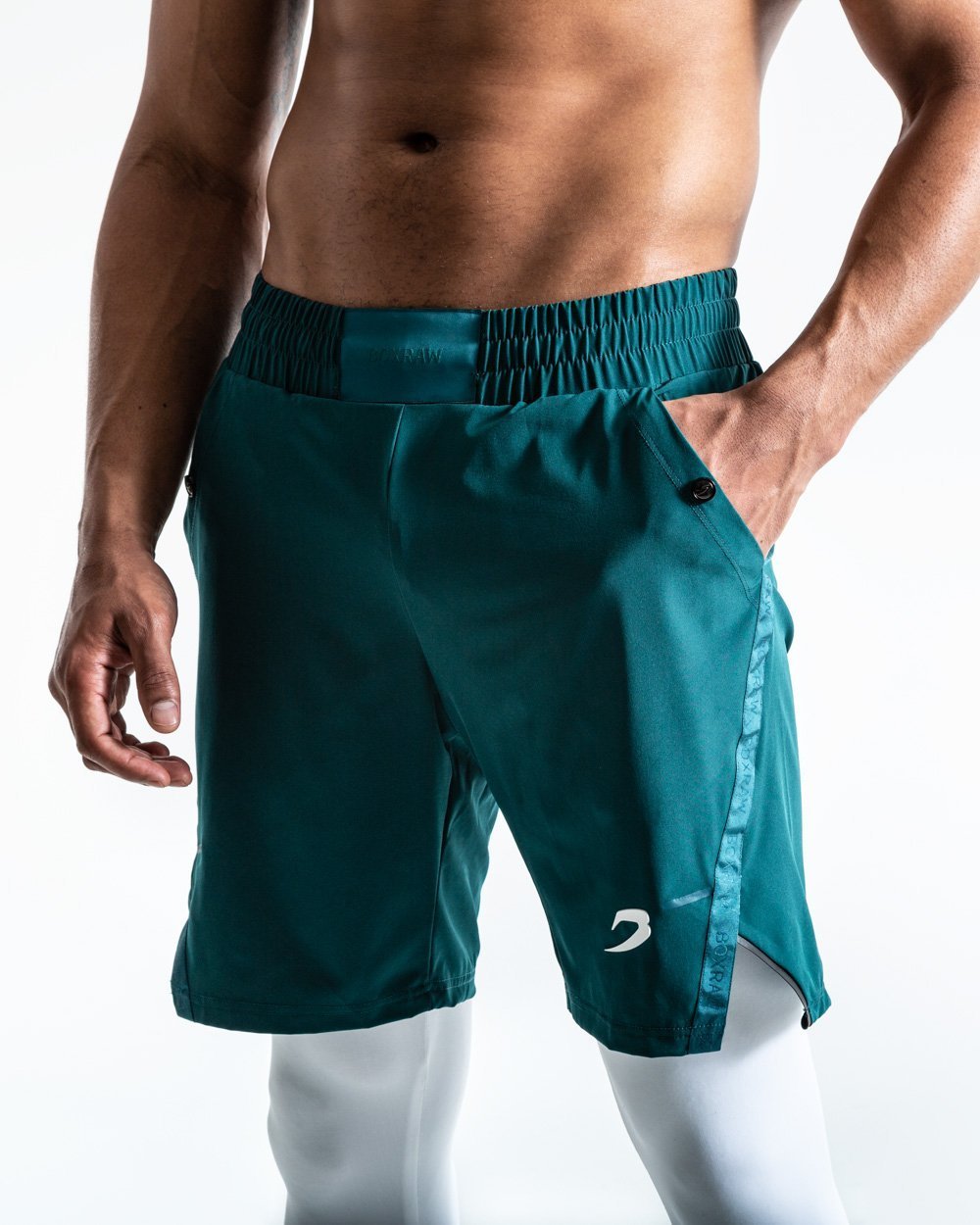 Man in green training shorts made from polyester with white compression leggings inside made from cotton with deep side pocket with a white strike logo.