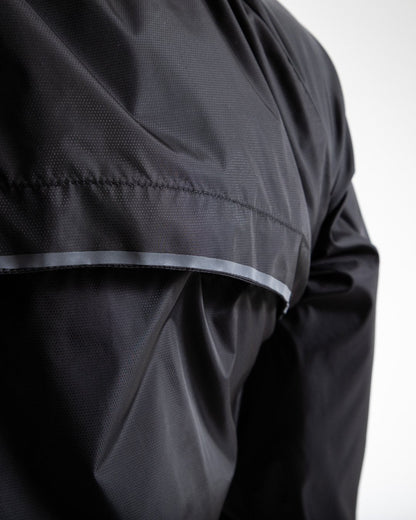 Man in black zipped windbreaker with hood and reflective big boxraw strike logo across left body panel made from nylon.
