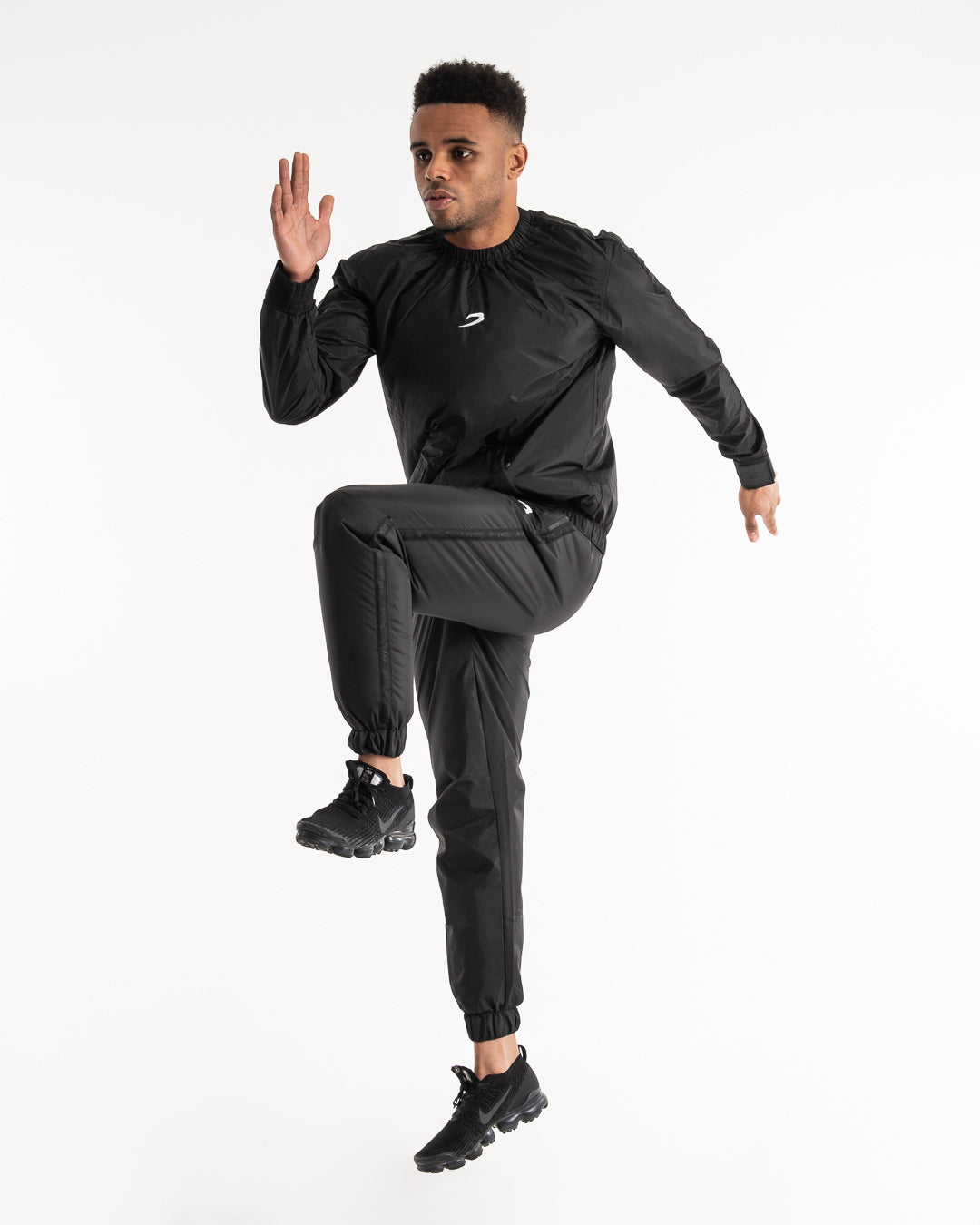 Man in a black sauna suit tracksuit with a white boxraw logo on the chest as well as adjustable wrist straps and made from polyester.