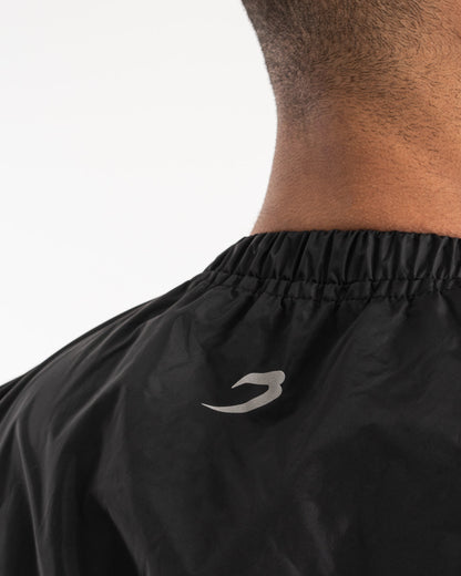 Man in a black sauna suit tracksuit with a white boxraw logo on the chest as well as adjustable wrist straps and made from polyester.