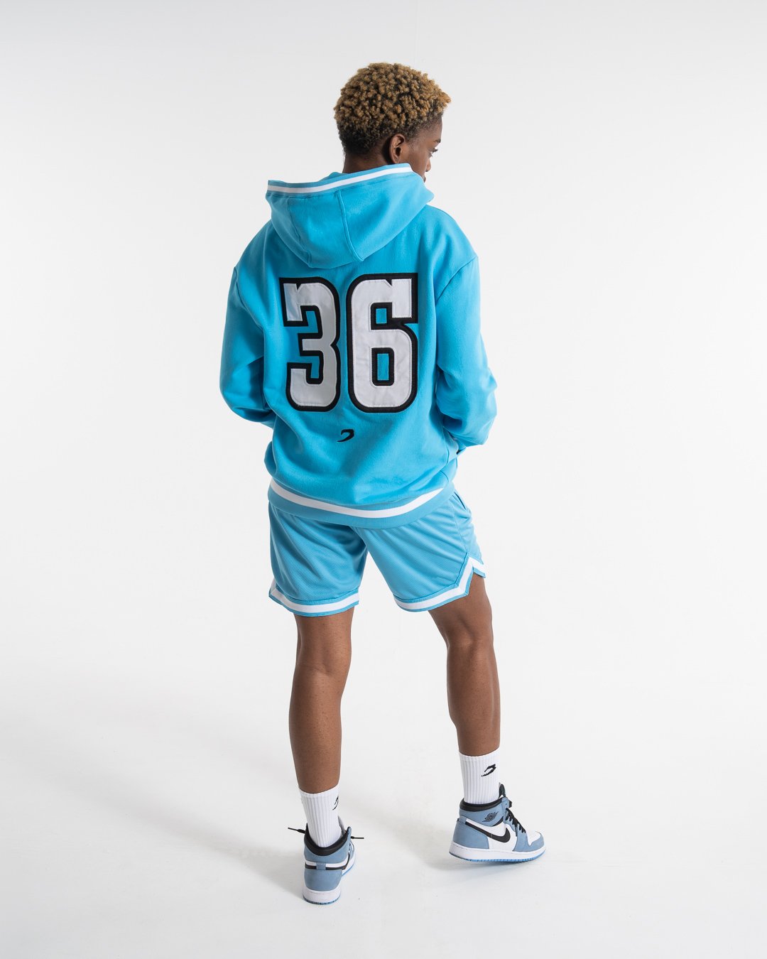 Women in a boxraw baby blue jumper with hood & kangaroo pocket made from cotton with the boxraw strike logo in white on the front and large 36 number on the back.
