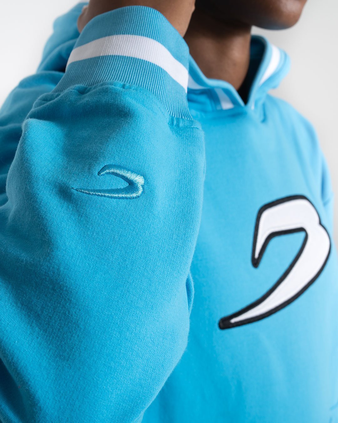 Women in a boxraw baby blue jumper with hood & kangaroo pocket made from cotton with the boxraw strike logo in white on the front and large 36 number on the back.