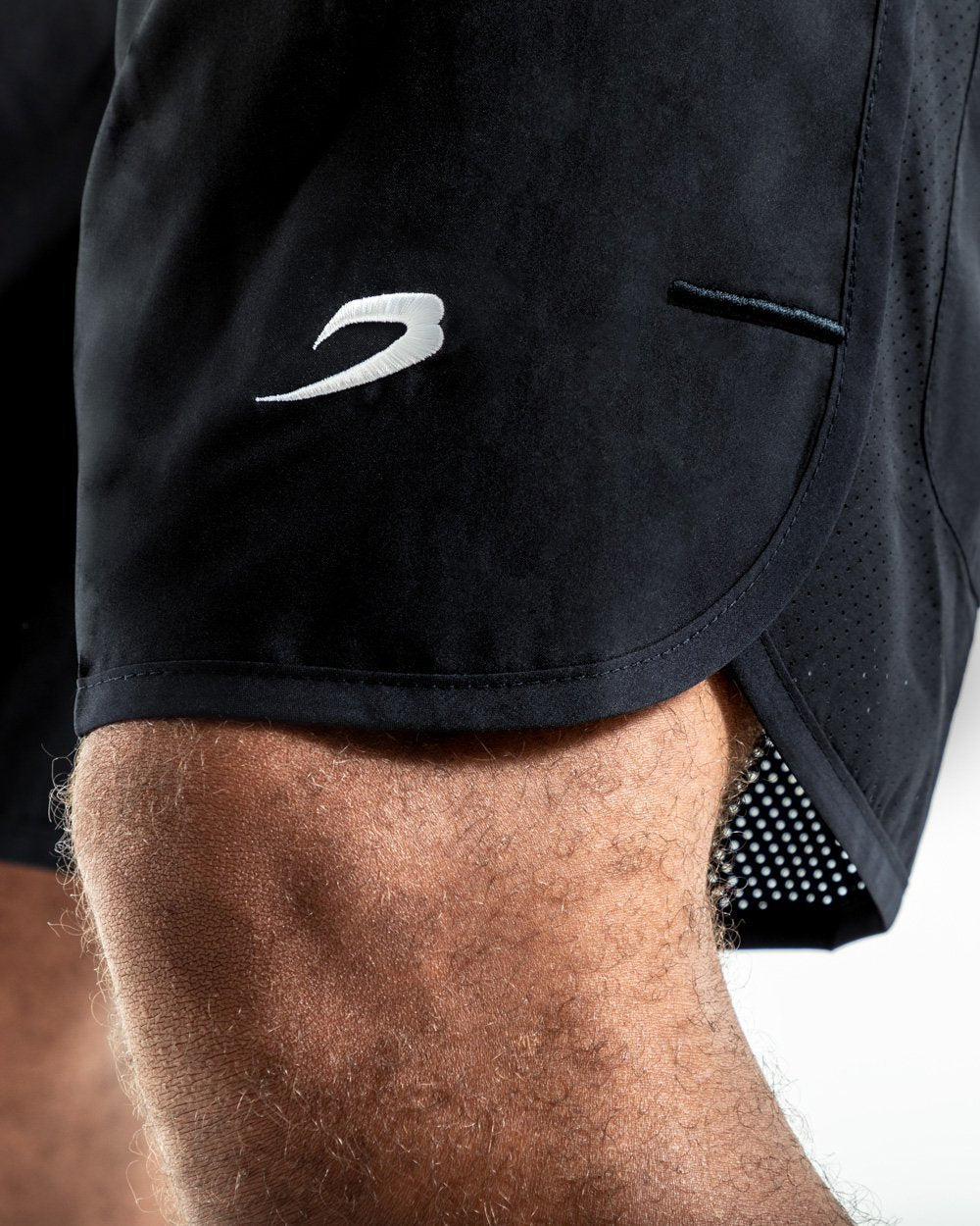 Man in black training shorts with adjustable waistband and side zipped pockets as well as an embroidered white boxraw strike logo.