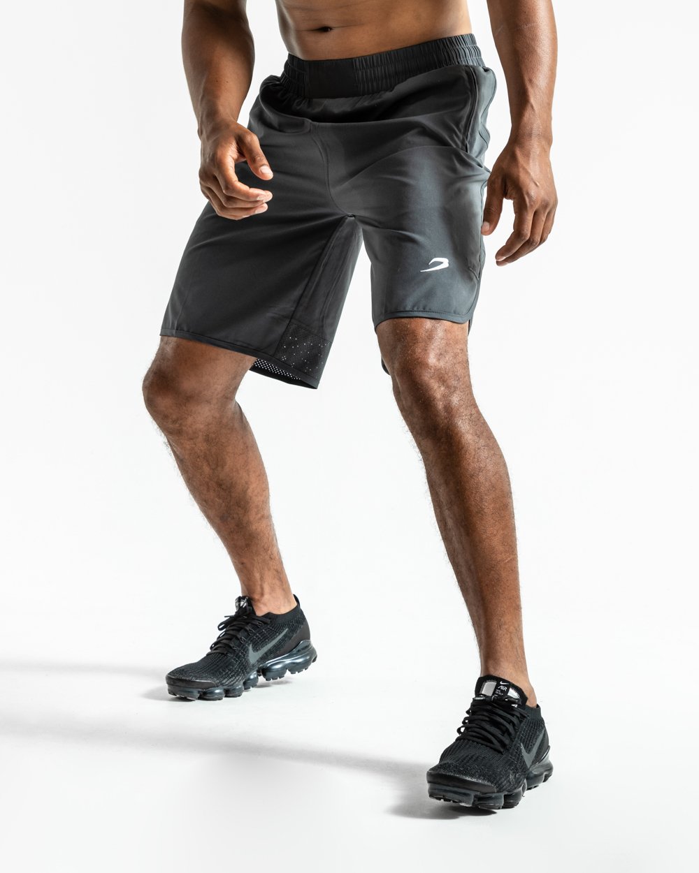 Man in charcoal training shorts with adjustable waistband and side zipped pockets as well as an embroidered white boxraw strike logo.