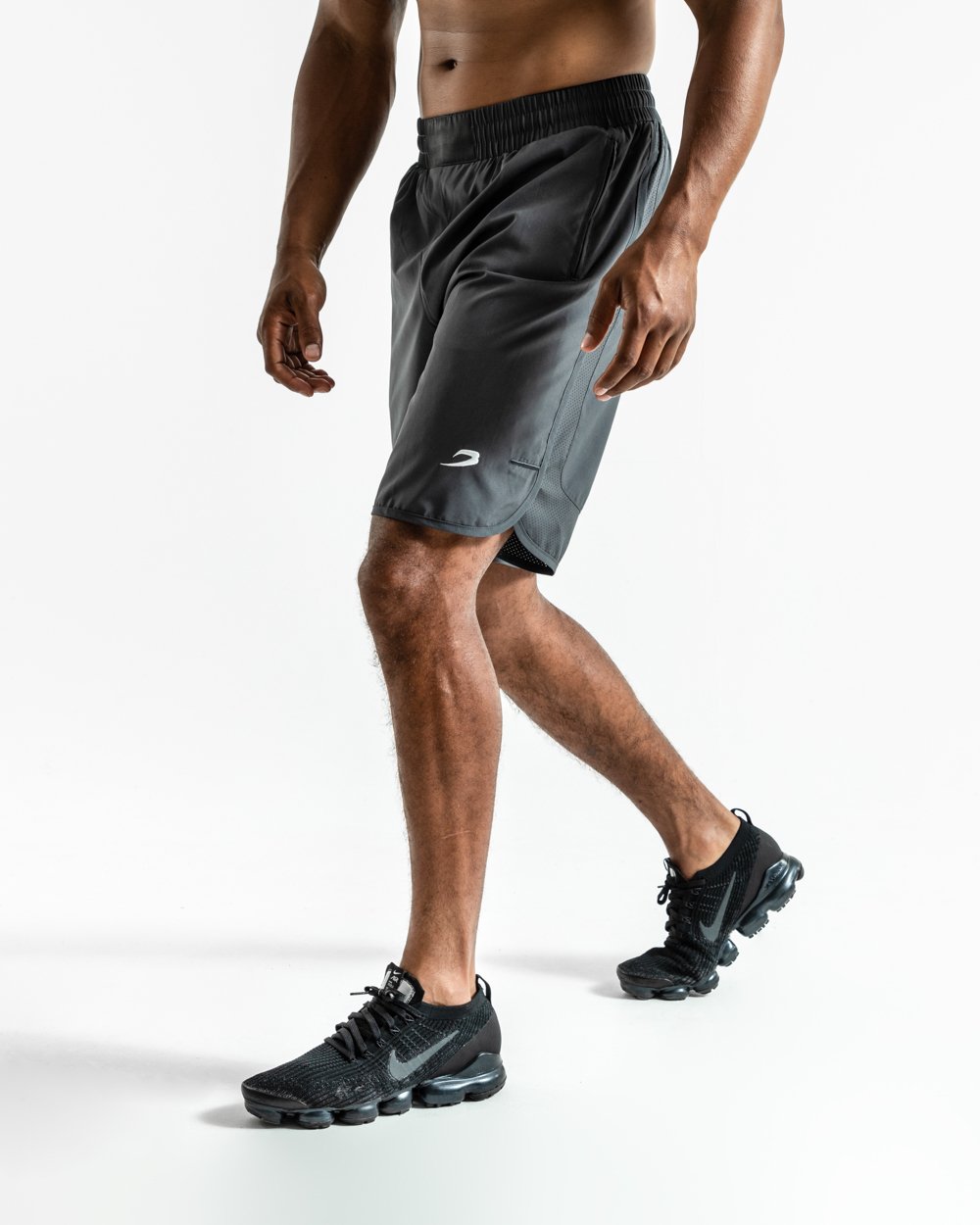 Man in charcoal training shorts with adjustable waistband and side zipped pockets as well as an embroidered white boxraw strike logo.