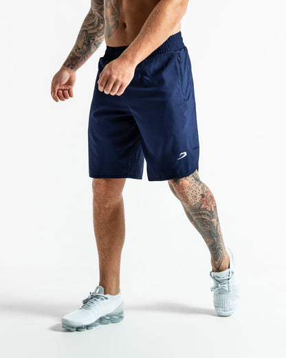 Man in navy training shorts with adjustable waistband and side zipped pockets as well as an embroidered white strike logo.
