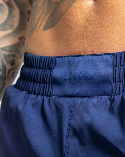 Man in navy training shorts with adjustable waistband and side zipped pockets as well as an embroidered white strike logo.