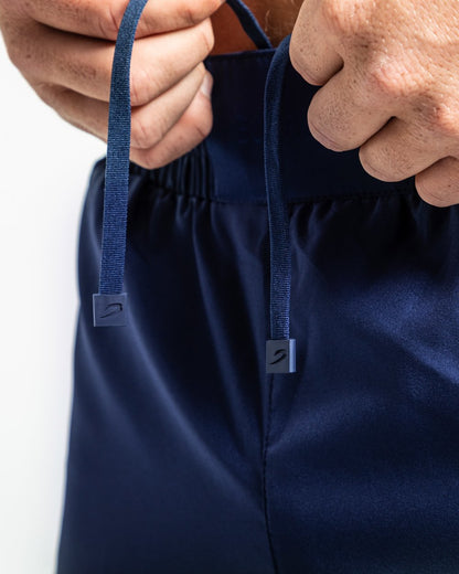 Man in navy training shorts with adjustable waistband and side zipped pockets as well as an embroidered white strike logo.