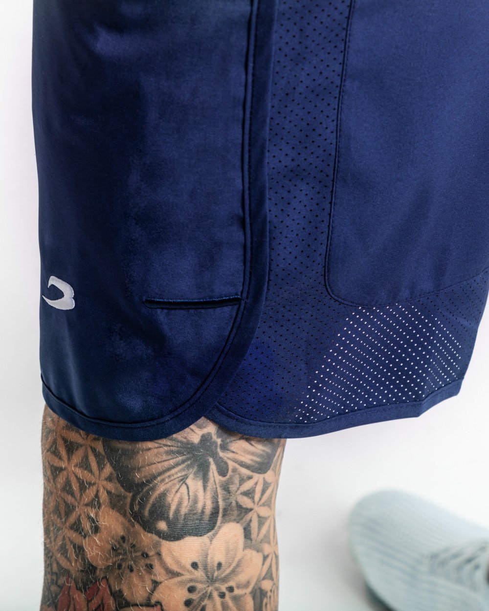 Man in navy training shorts with adjustable waistband and side zipped pockets as well as an embroidered white strike logo.