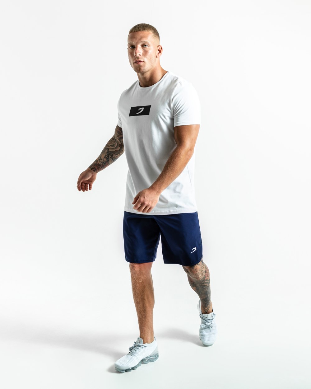 Man in navy training shorts with adjustable waistband and side zipped pockets as well as an embroidered white strike logo.