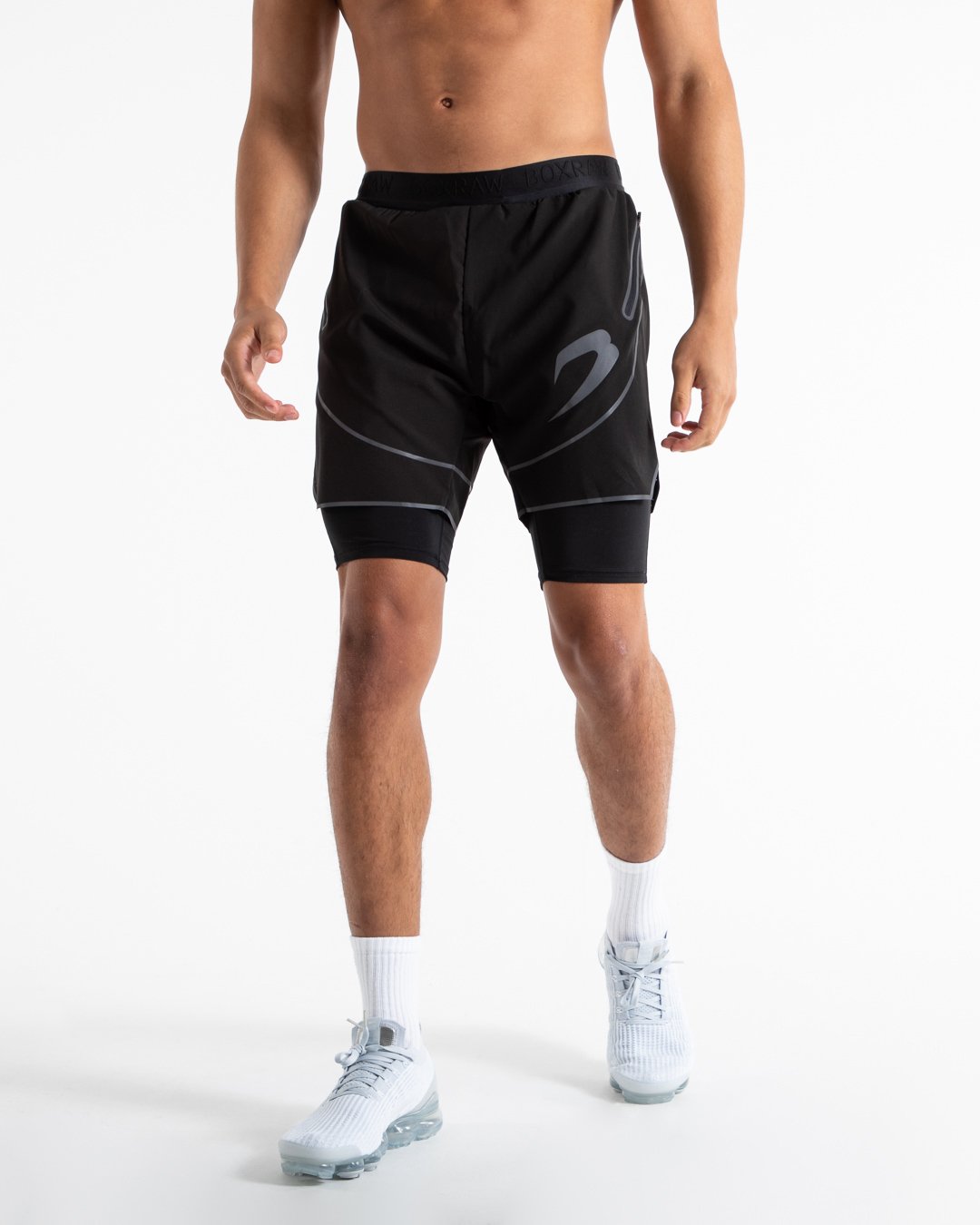 Man in black shorts with compression shorts underlayer with reflective detailing and side zipped pockets