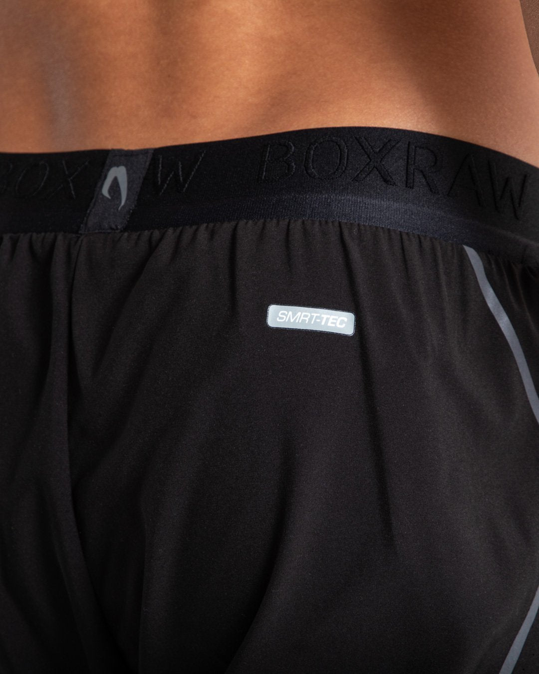 Man in black shorts with compression shorts underlayer with reflective detailing and side zipped pockets