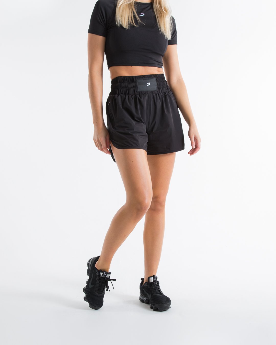 Women in black high waisted shorts with woven strike logo waistband patch