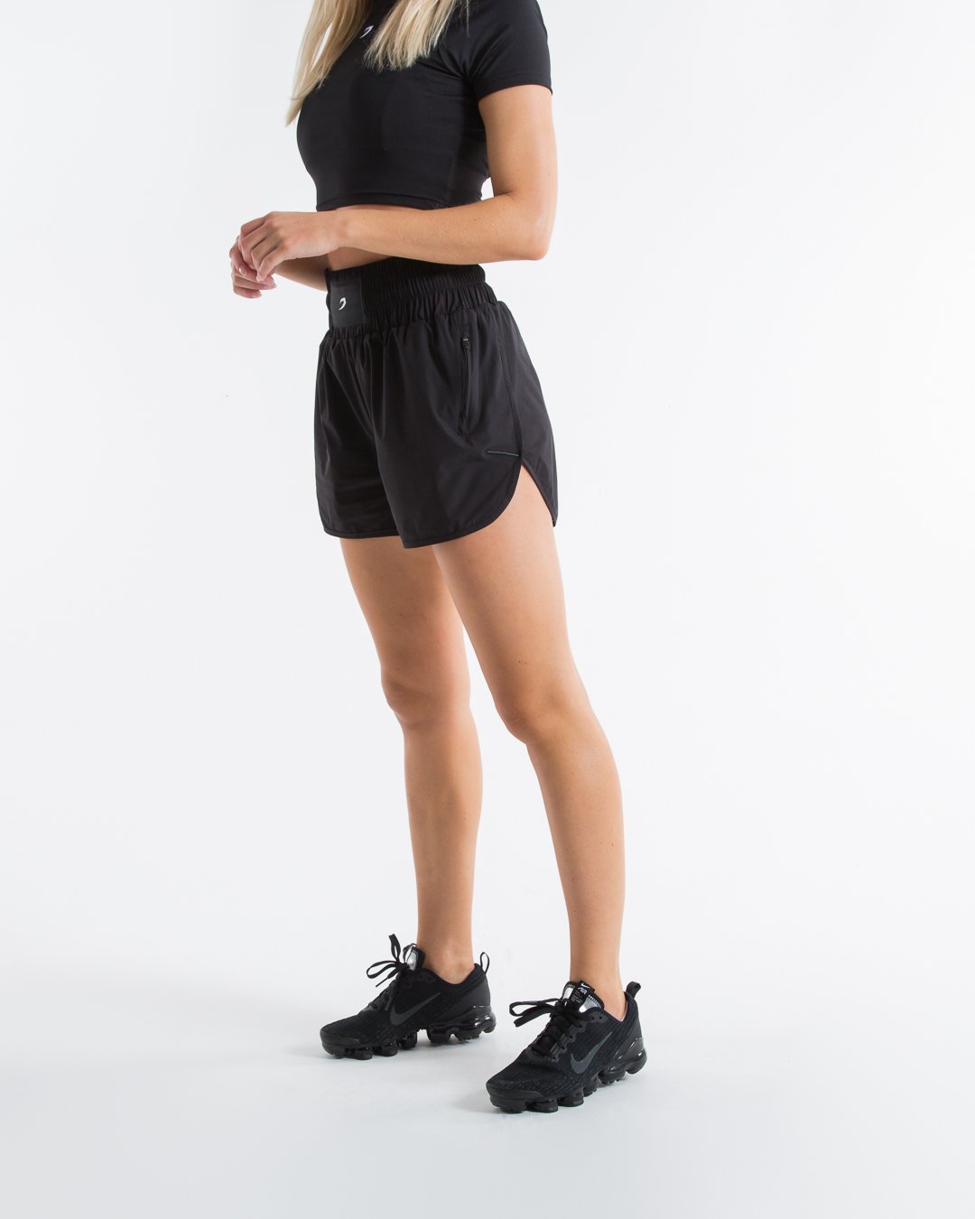 Women in black high waisted shorts with woven strike logo waistband patch