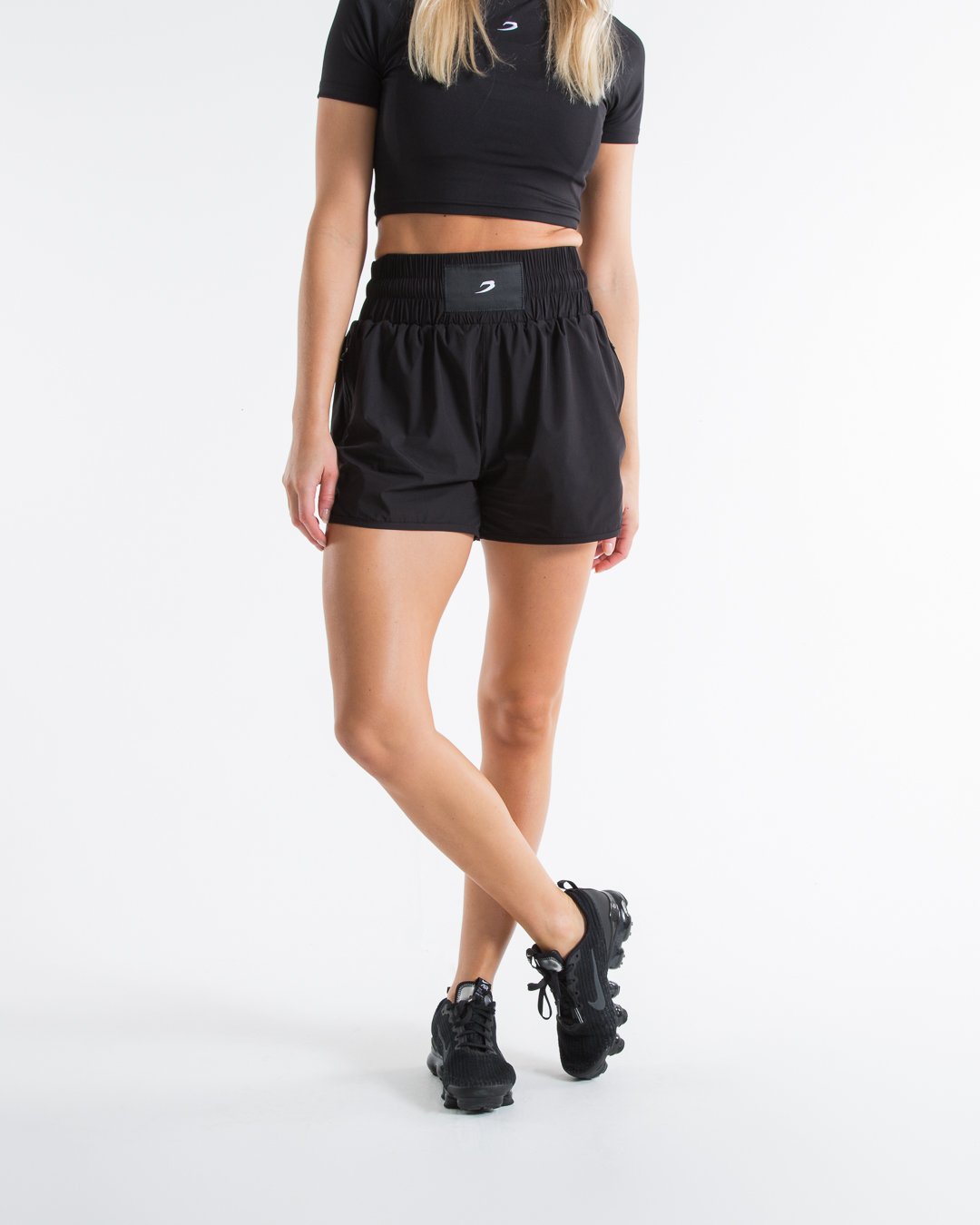 Women in black high waisted shorts with woven strike logo waistband patch