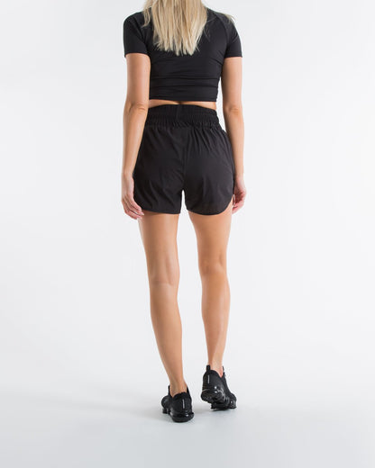 Women in black high waisted shorts with woven strike logo waistband patch