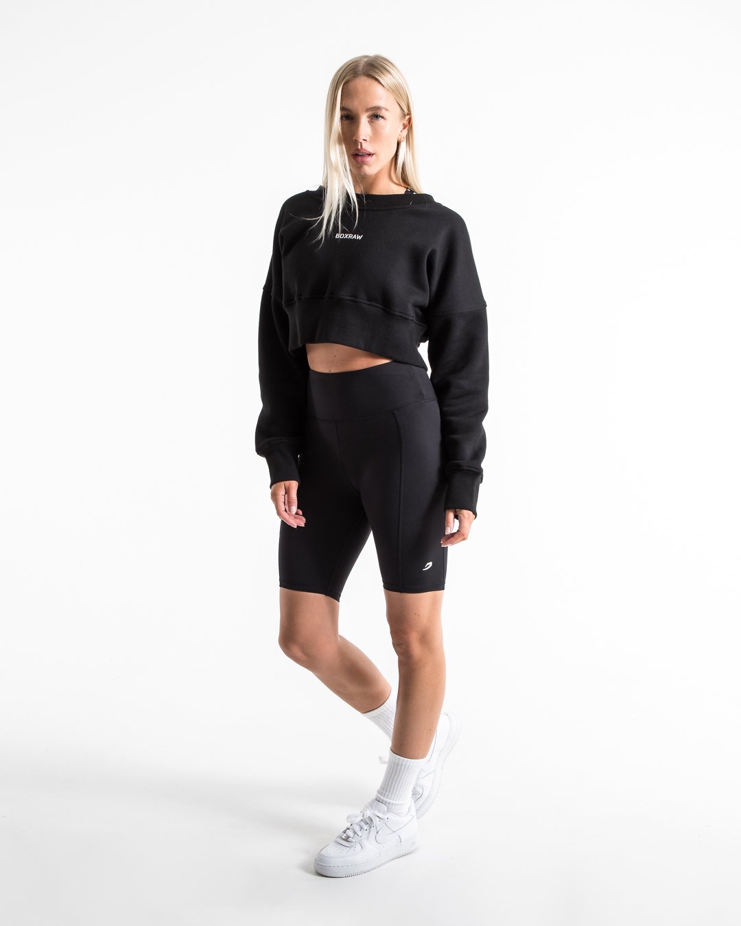 Women in black high wasted cycling shorts with a compressed fit and hidden side pockets as well as a 3D white strike logo