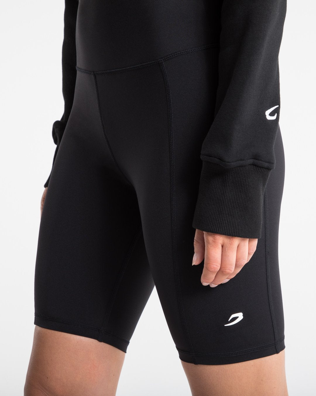 Women in black high wasted cycling shorts with a compressed fit and hidden side pockets as well as a 3D white strike logo