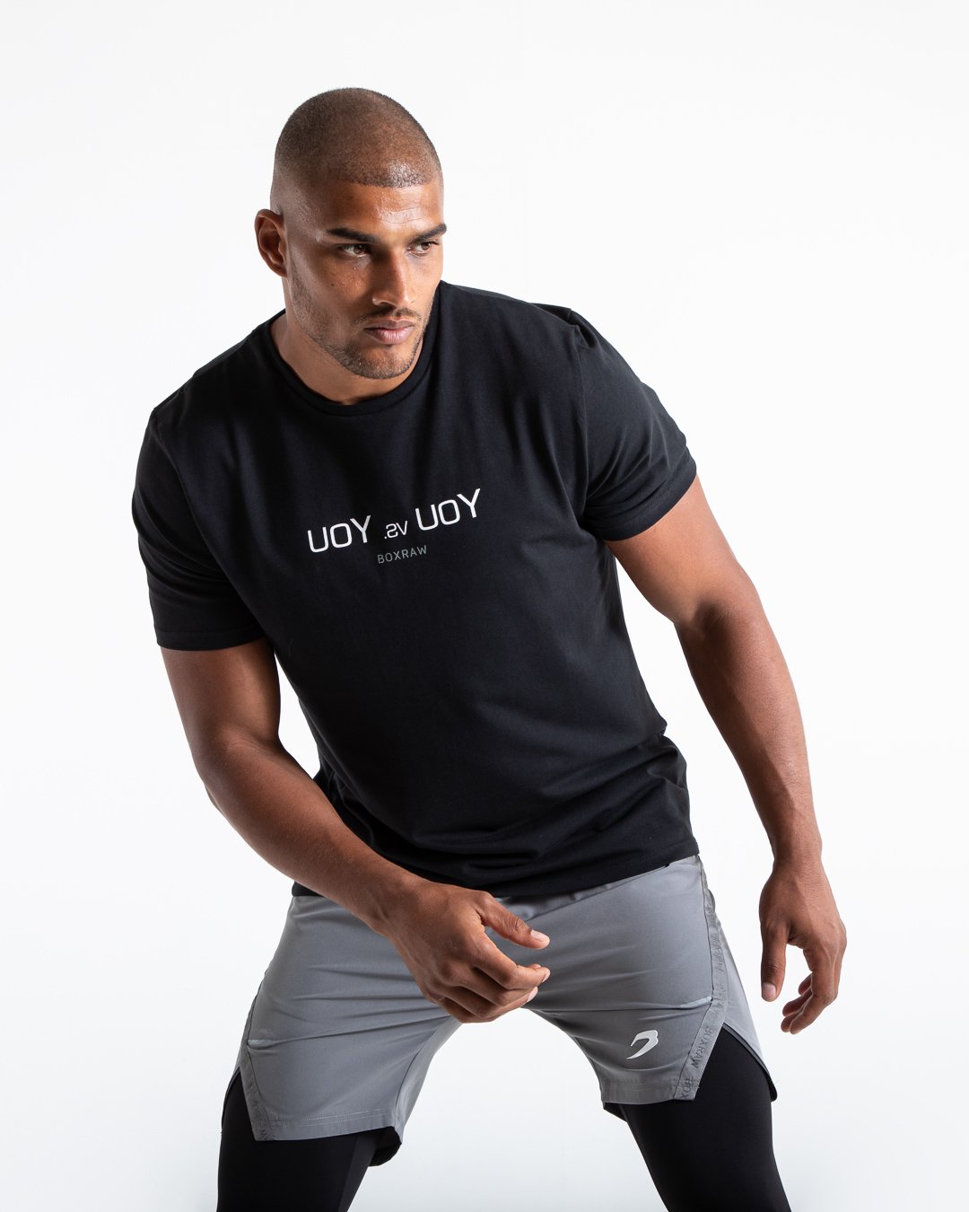 Man in black slim fit cotton t-shirt with reversed you vs you text in white on chest.