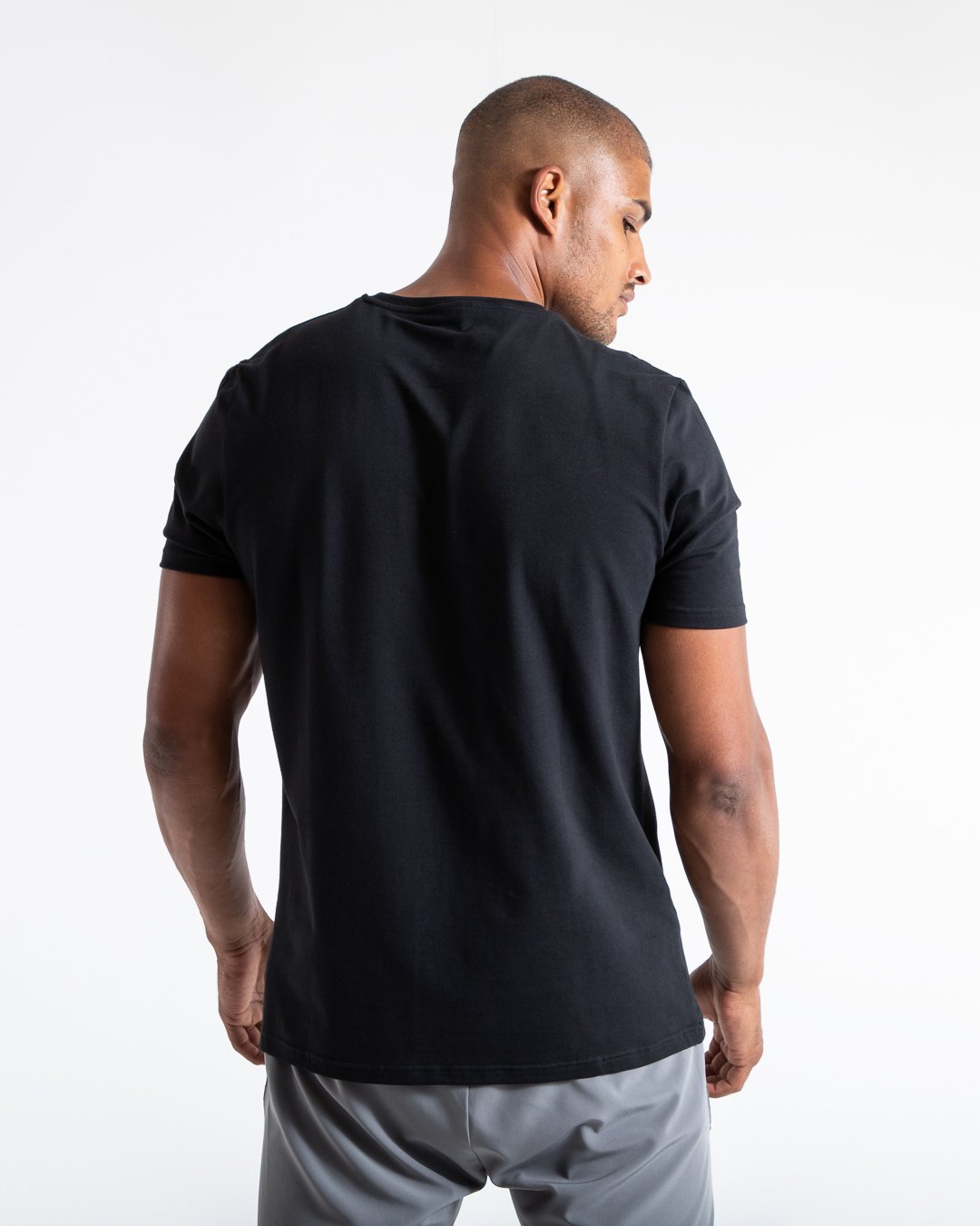 Man in black slim fit cotton t-shirt with reversed you vs you text in white on chest.