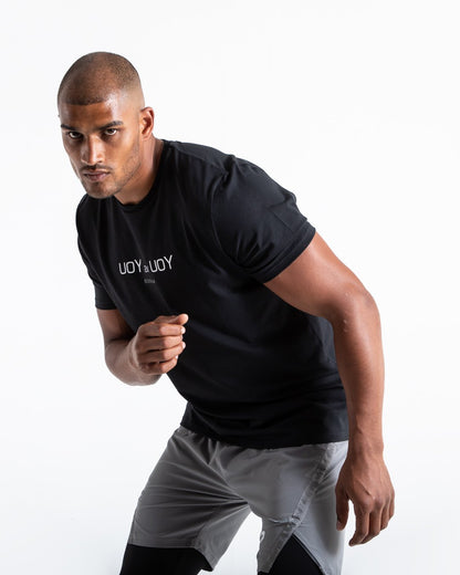 Man in black slim fit cotton t-shirt with reversed you vs you text in white on chest.