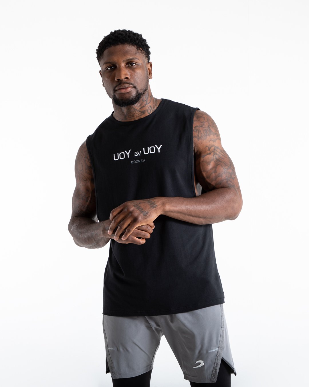 Man in black slim fit cotton muscle tank with reversed you vs you text in white on chest.